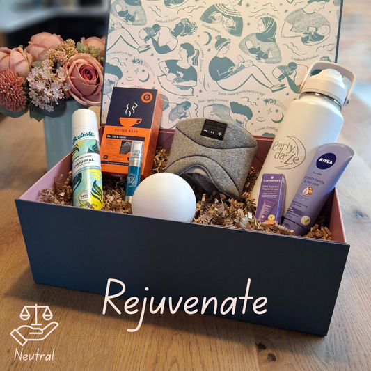 Gift box labeled 'Rejuvenate' with various items including a water bottle, face mask, and other products on a wooden surface.